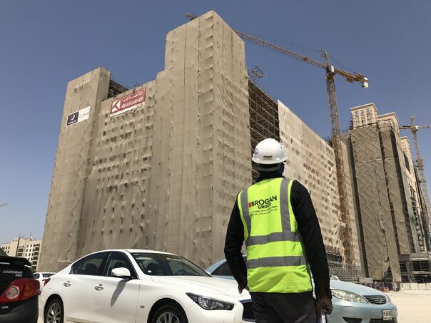 scaffolding around huge building in uae, person with hard hat looking up at the building